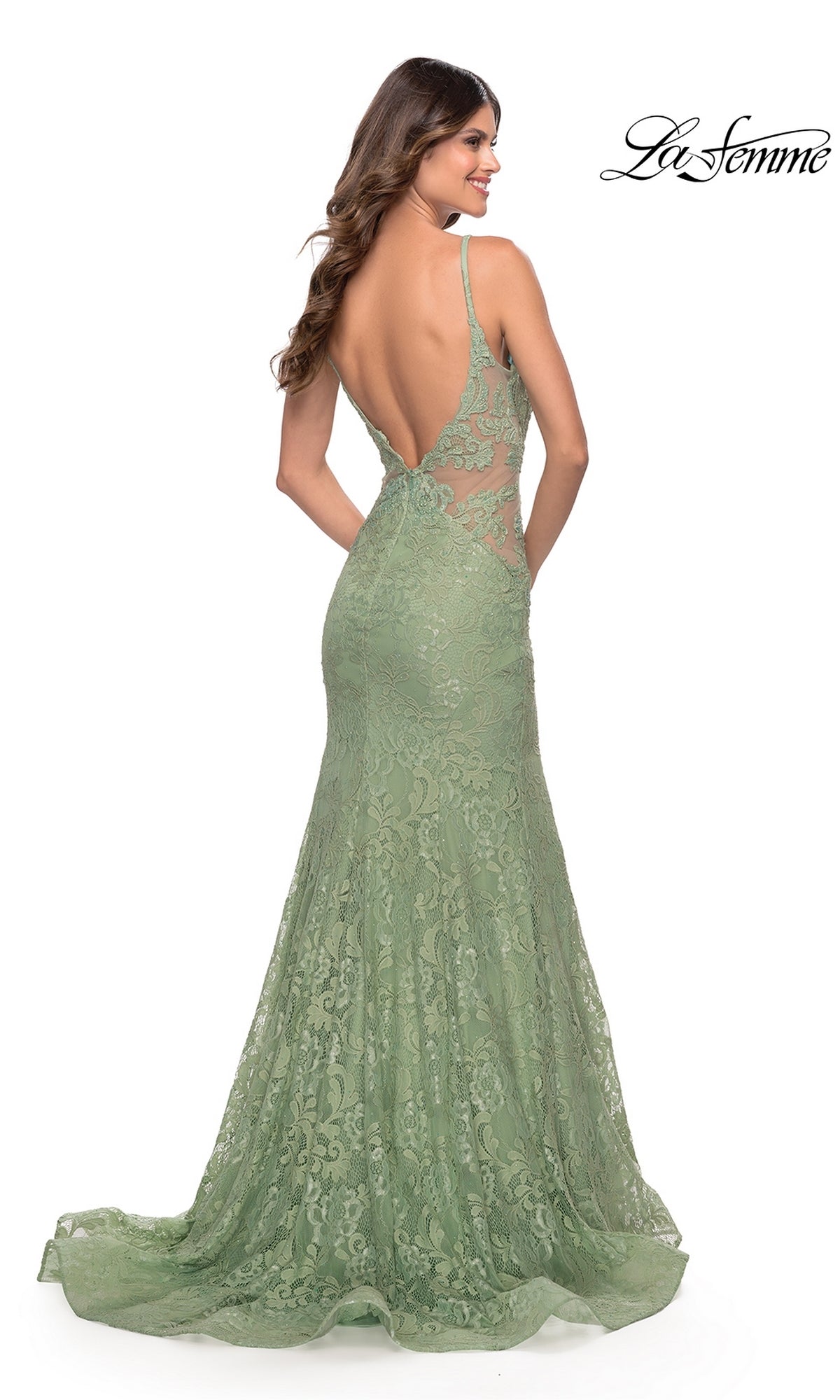 A woman faces away from the camera in the La Femme 31512 Long Lace Mermaid Prom Dress, a floor-length sage green gown featuring delicate lace, thin straps, and an open back.